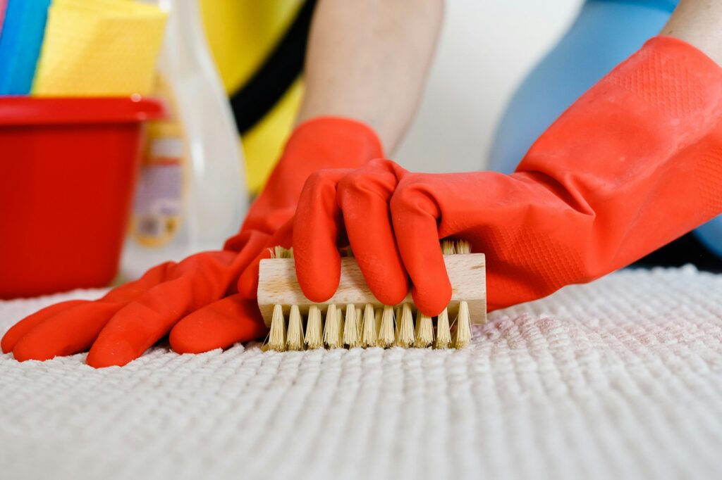 close up of woman in rubber gloves cleaning carpet at home